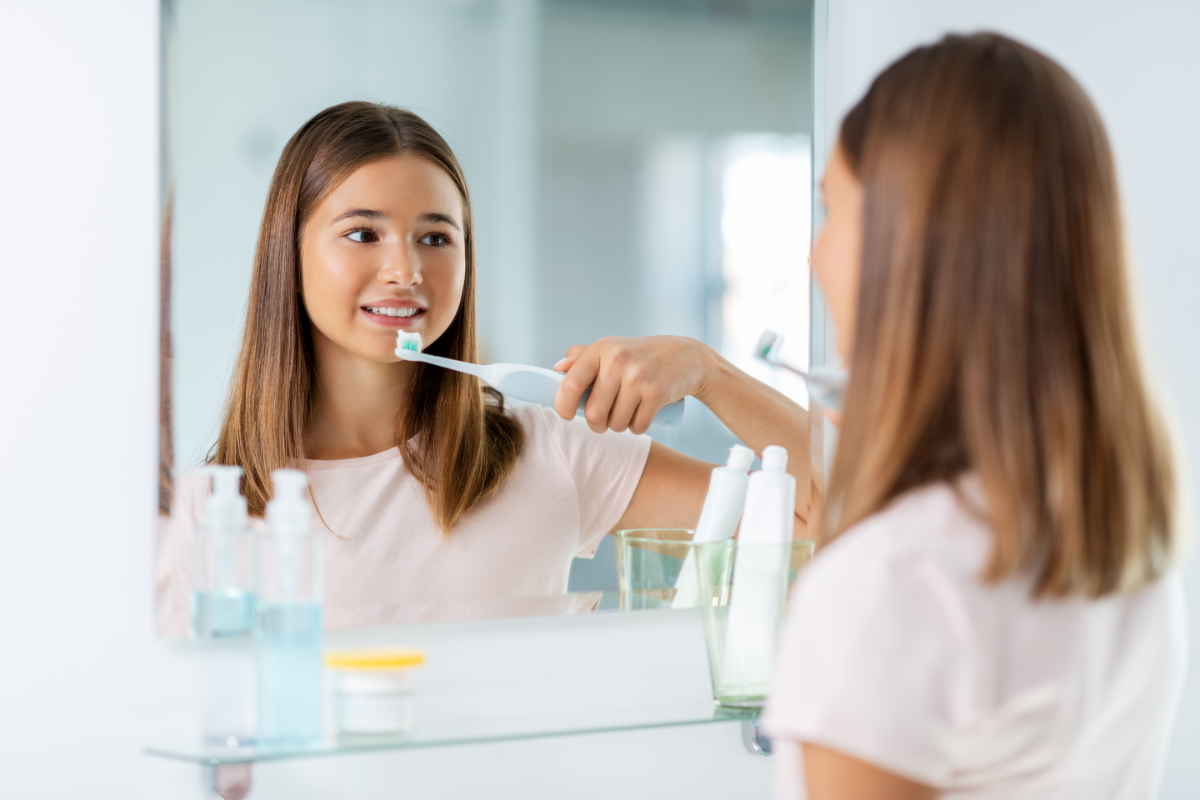 Femme utilisant une brosse à dents électrique